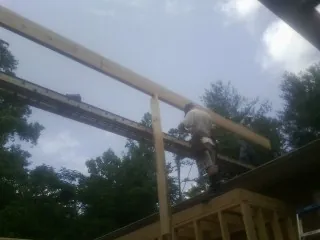 Carpenter setting a ridge beam over a new addition frame — Ice Dam Removal by Roofing Brothers in Burnt Hills