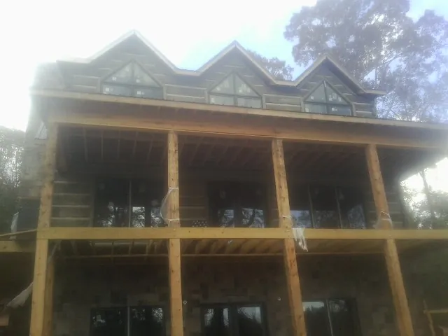 Dormers and porch framing on a large log home under construction — Roof Coating work by our crew in Burnt Hills
