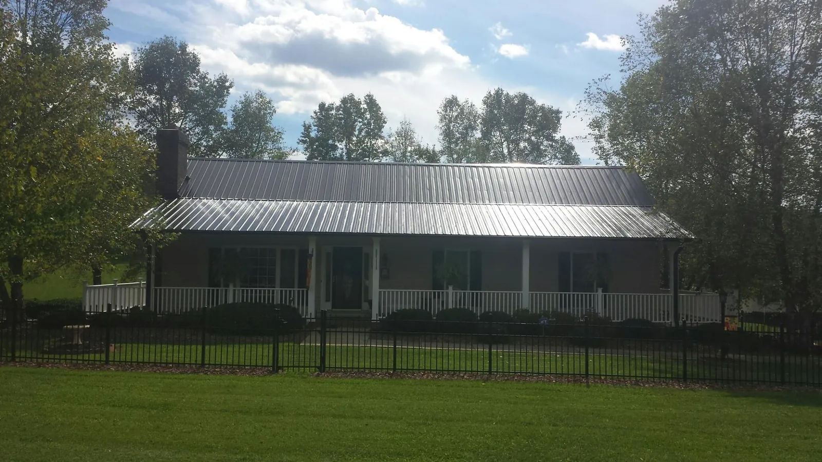 Gray metal roof on a brick ranch with a full width front porch — Gutter Guard Installation work by our crew in Burnt Hills